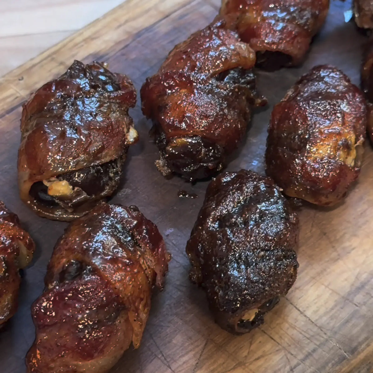 Stuffed Smoked Candied Jalapeño Whomp Bacon-Wrapped Dates cooked and displayed on a butchers block